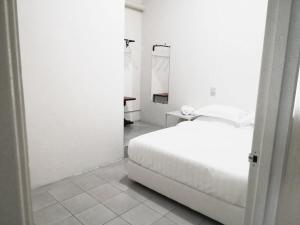 a white bedroom with a bed and a table at Ozzy Lodge Semporna in Semporna