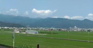 a field with a city and mountains in the background at 宜蘭樸實園民宿 in Jiaoxi