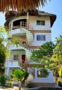 a white building with stairs and a thatch roof at Simba House in Watamu