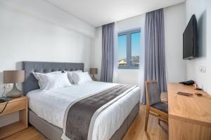 a bedroom with a bed and a desk and a television at Glyfada Riviera Hotel in Athens