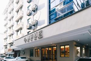 Hangzhou Yuqi Hotel في هانغتشو: مبنى فيه سيارات تقف امامه