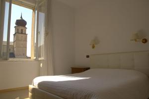 a bedroom with a bed and a window with a clock tower at Hotel Venezia in Trento