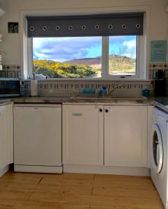 a kitchen with a sink and a window and a dishwasher at The Stroops in Helmsdale