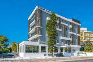 an apartment building with a tree in front of it at Glyfada Riviera Hotel in Athens