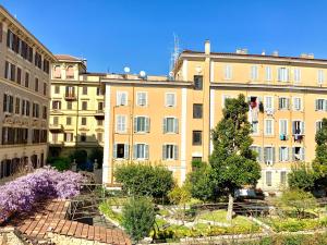 un grupo de edificios con flores púrpuras delante de ellos en Le Rondini a Roma, en Roma