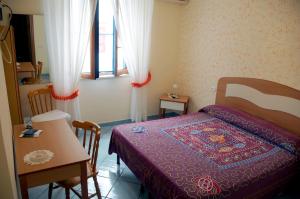 1 dormitorio con cama, mesa, mesa y sillas en Hotel Villa Del Mare, en Bacoli