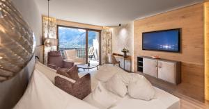 Hotel Sonnbichl في تيرولو: غرفة معيشة بها أريكة وتلفزيون