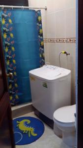 a bathroom with a toilet and a blue shower curtain at Apartamento Residencial Costa Azul in Santo Domingo