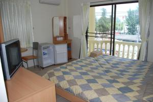 a bedroom with a bed and a television and a balcony at TK Guesthouse in Cha Am