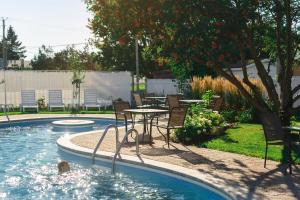 a pool with a table and chairs next to a table and a table at Hotel Le Montagnais in Saguenay