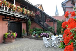 un patio con tavoli e fiori su un edificio di Gites-Weyer La maison a Bergheim