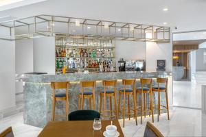 a bar with chairs and a counter with drinks at Glyfada Riviera Hotel in Athens