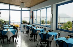 a restaurant with blue tables and chairs and windows at Hotel Villa Del Mare in Bacoli
