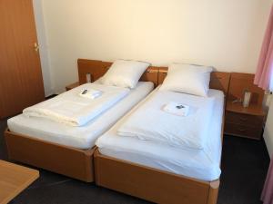 two beds in a hotel room with white sheets at Hotel Mivano Lehrte in Lehrte
