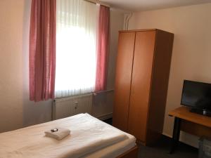 a bedroom with a bed and a dresser and a window at Hotel Mivano Lehrte in Lehrte