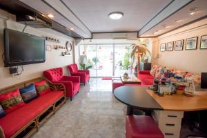 a waiting room with red couches and a tv at Maria Room HuaHin in Hua Hin