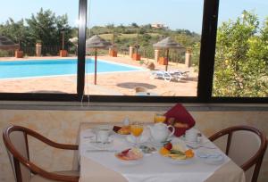 a table with breakfast food and a view of a pool at Quinta dos Poetas Nature Hotel & Apartments in Olhão