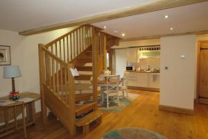 a living room with a wooden staircase and a kitchen at Welsh Apple Barn in Chepstow