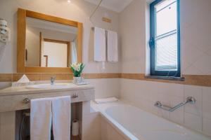 a bathroom with a sink and a tub and a mirror at Quinta dos Poetas Nature Hotel & Apartments in Olhão