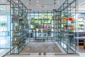 a glass case filled with bottles in a room at Glyfada Riviera Hotel in Athens