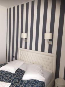 a bed with two lamps on a striped wall at Hotel Centrale in Trieste