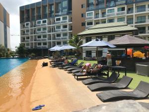 a group of people laying on lounge chairs next to a pool at Laguna Beach Resort 2 in Jomtien Beach