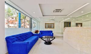 uma sala de estar com um sofá azul e uma mesa em Treebo Trend Blu Orchid em Bangalore