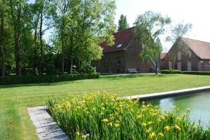 een huis met een vijver en bloemen in de tuin bij In 't Groen in Watou