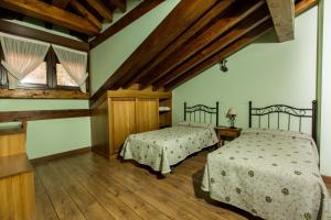 two beds in a room with wooden floors at La Dobra de liebana in Cambarco