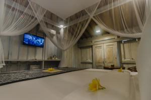 a bedroom with a bed with curtains and a tv at Green Taman Ubud by Prasi in Ubud