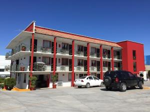 ein rotweißes Gebäude mit Autos auf einem Parkplatz in der Unterkunft Hotel Descanso Inn in Tijuana