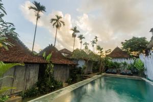 a swimming pool in front of a house with palm trees at Green Taman Ubud by Prasi in Ubud