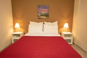 1 dormitorio con 1 cama roja y 2 lámparas en Seaside Apartments-Angela, en Kalí Limenes