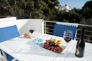una mesa blanca con dos copas de vino y uvas en Seaside Apartments-Angela, en Kalí Limenes