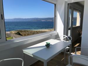 una mesa blanca y una ventana con vistas al océano en OH LA LIFE PORTOSIN LA PLAYA, en Portosín