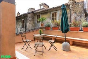 un patio con mesa, sillas y sombrilla en Domus Colonnato su Villa d'Este, en Tívoli