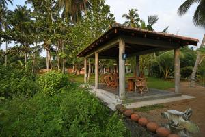 a pavilion with a table and chairs in a park at Hettimulla River House in Bentota +8 photos