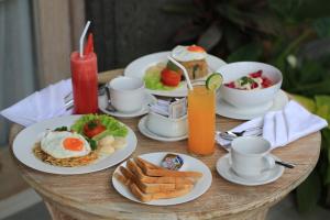 a table with plates of breakfast food on it at Green Taman Ubud by Prasi in Ubud