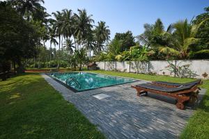 a swimming pool with a bench next to a yard at Hettimulla River House in Bentota