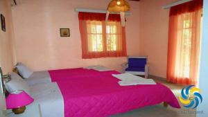 um quarto com uma cama grande e um cobertor rosa em Errika em Ipsos