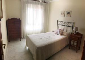 ein Schlafzimmer mit einem Bett, einer Kommode und einem Fenster in der Unterkunft Sub-ático con parking en el centro de Estepona in Estepona