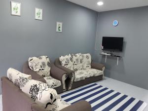 a living room with two chairs and a tv at Anis Homestay Gua Musang in Gua Musang