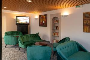 a waiting room with green chairs and a television at Hotel Majestic Alsace - Strasbourg Nord in Niederbronn-les-Bains