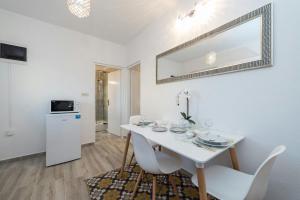 a white dining room with a white table and chairs at Apartment Maja in Novalja in Novalja