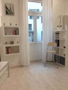 Cette chambre blanche dispose d'une chaise et d'une fenêtre. dans l'établissement Isola Flat, à Milan