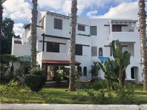 a white building with palm trees in front of it at Bahia Smir in Tétouan