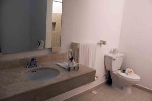 ein Badezimmer mit Waschbecken, Toilette und Spiegel in der Unterkunft Sotavento Hotel & Yacht Club in Cancún