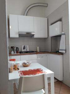 una cucina con armadi bianchi e tavolo e sedie bianchi di Casa Elisa a Cosenza