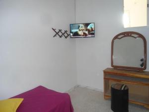 Zimmer mit einem TV und einem Spiegel in der Unterkunft Auberge Alferdaous in Tataouine