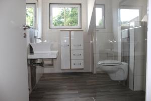 a white bathroom with a toilet and a sink at Stadthaus Edel - Apartment Binz in Remscheid